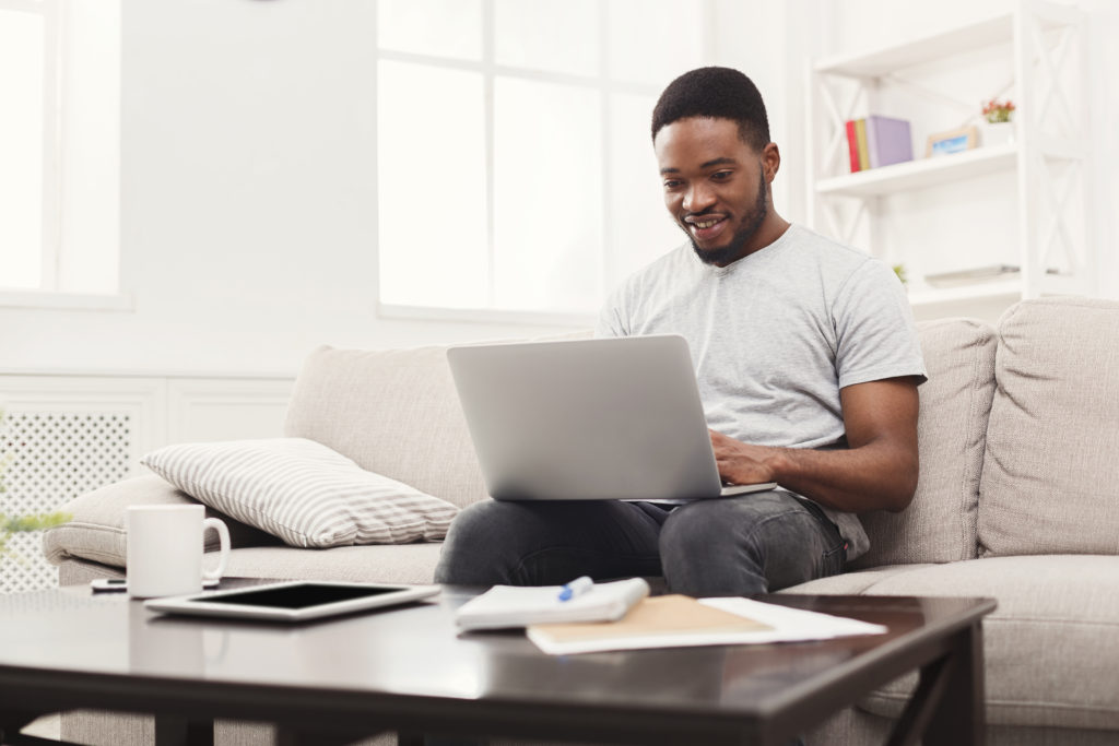 Young Man At Home Messaging Online On Laptop