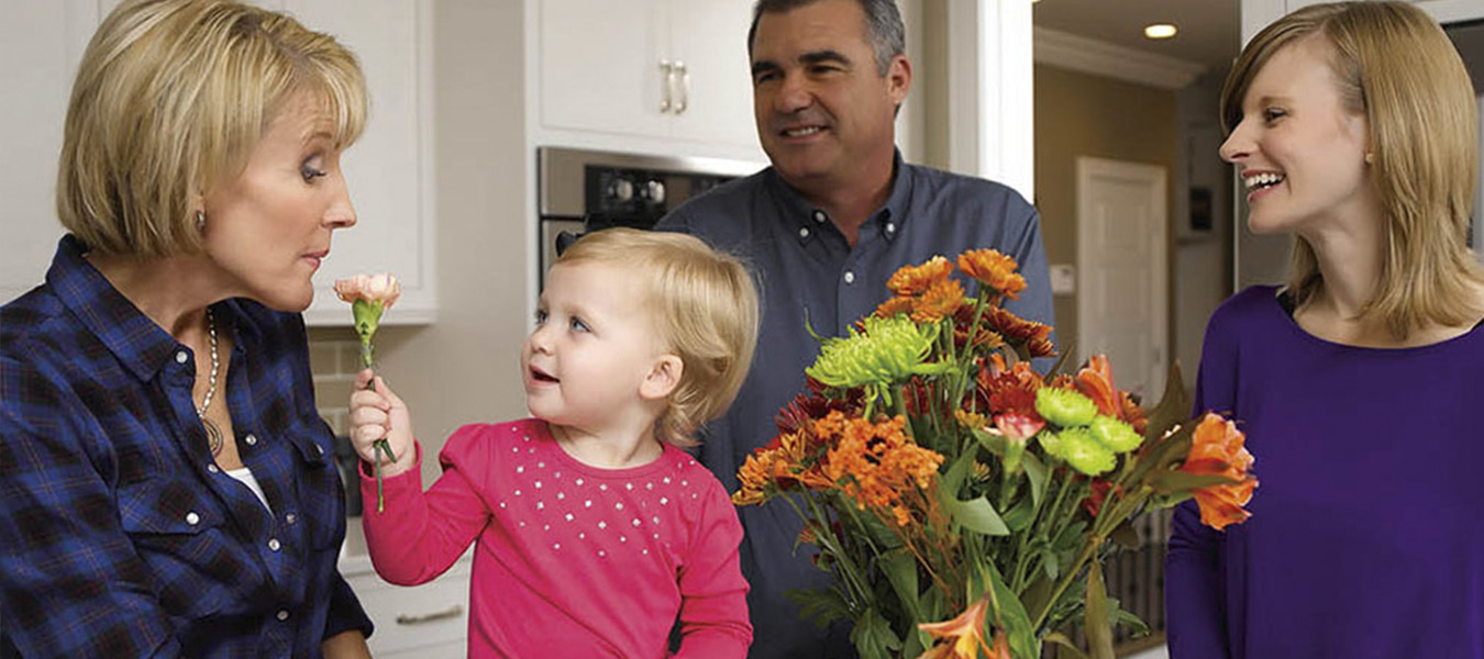 family smelling flowers in a kitchen