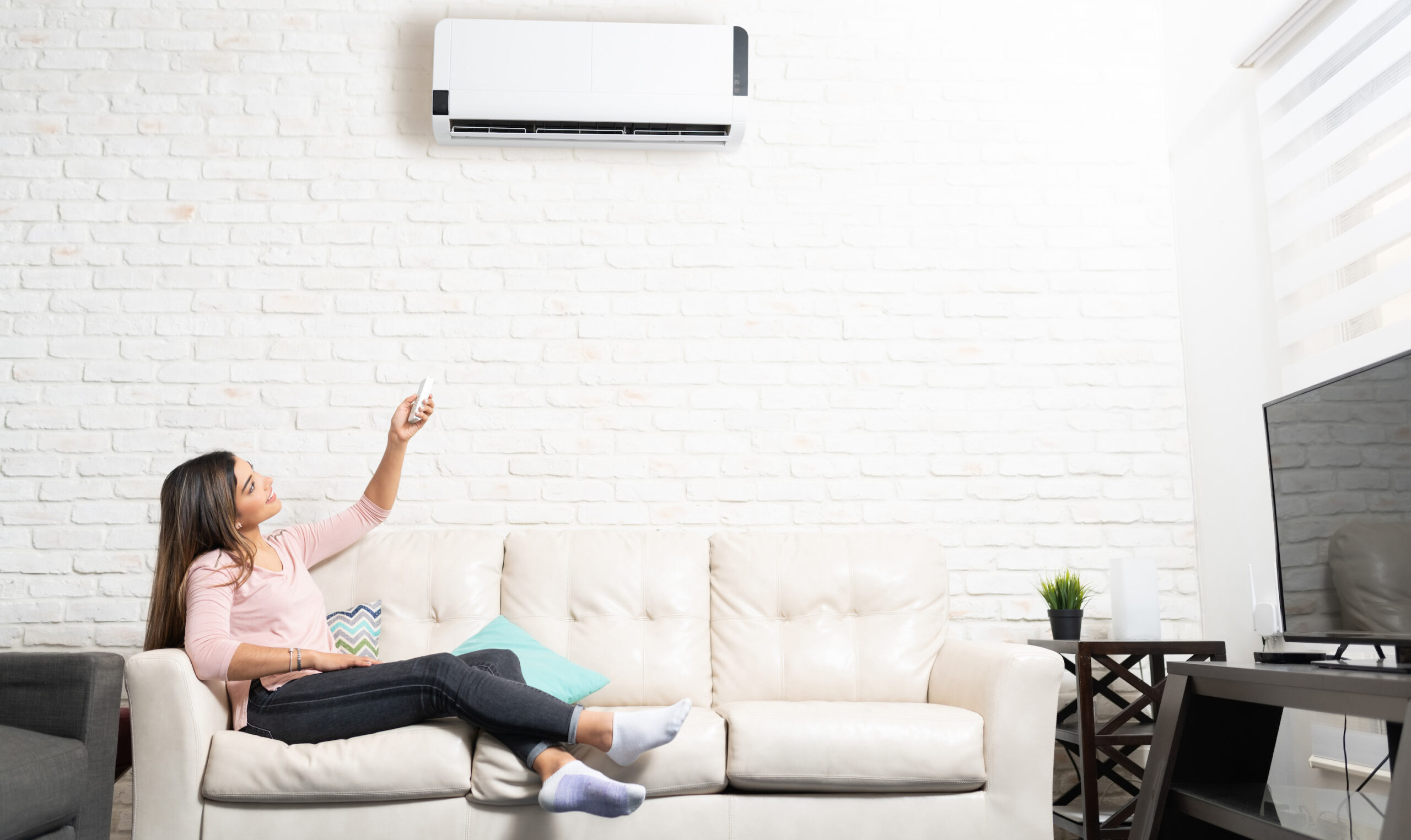Woman Turning On Her Ductless Mini Split Air Conditioner At Home
