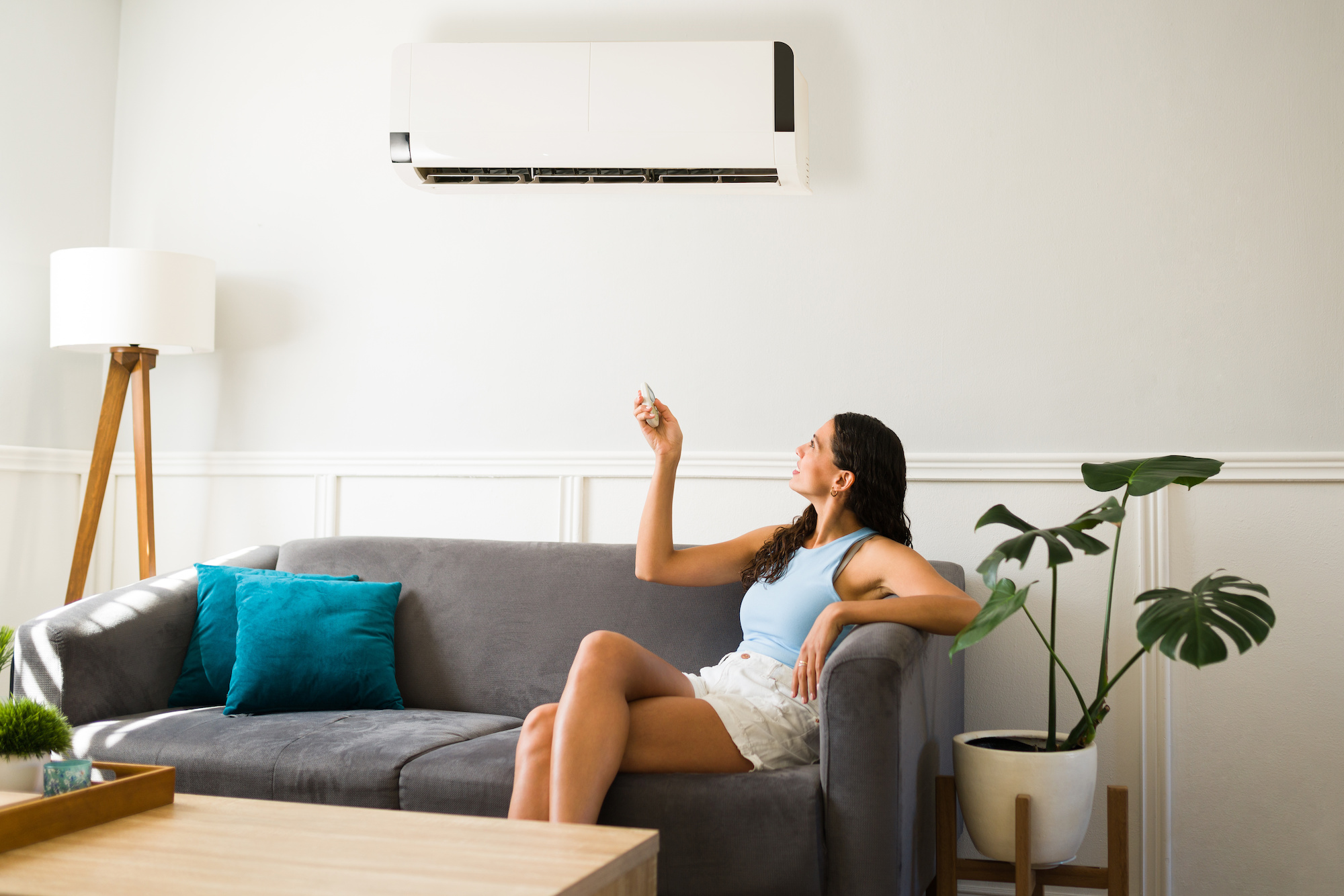 A young woman at home using her refrigerated air conditioner to stay cool while sitting in her living room.