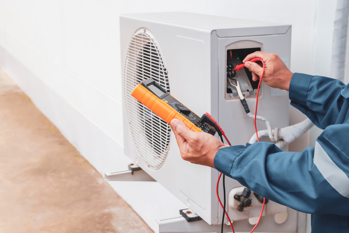 A professional providing maintenance on a white air conditioning system in El Paso.