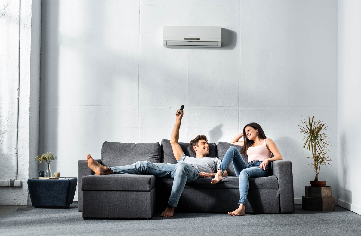 Two people sitting on a couch while turning on their air conditioning in El Paso.