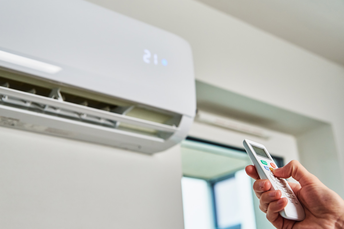 A wall AC with a hand using a remote to turn it on in El Paso.