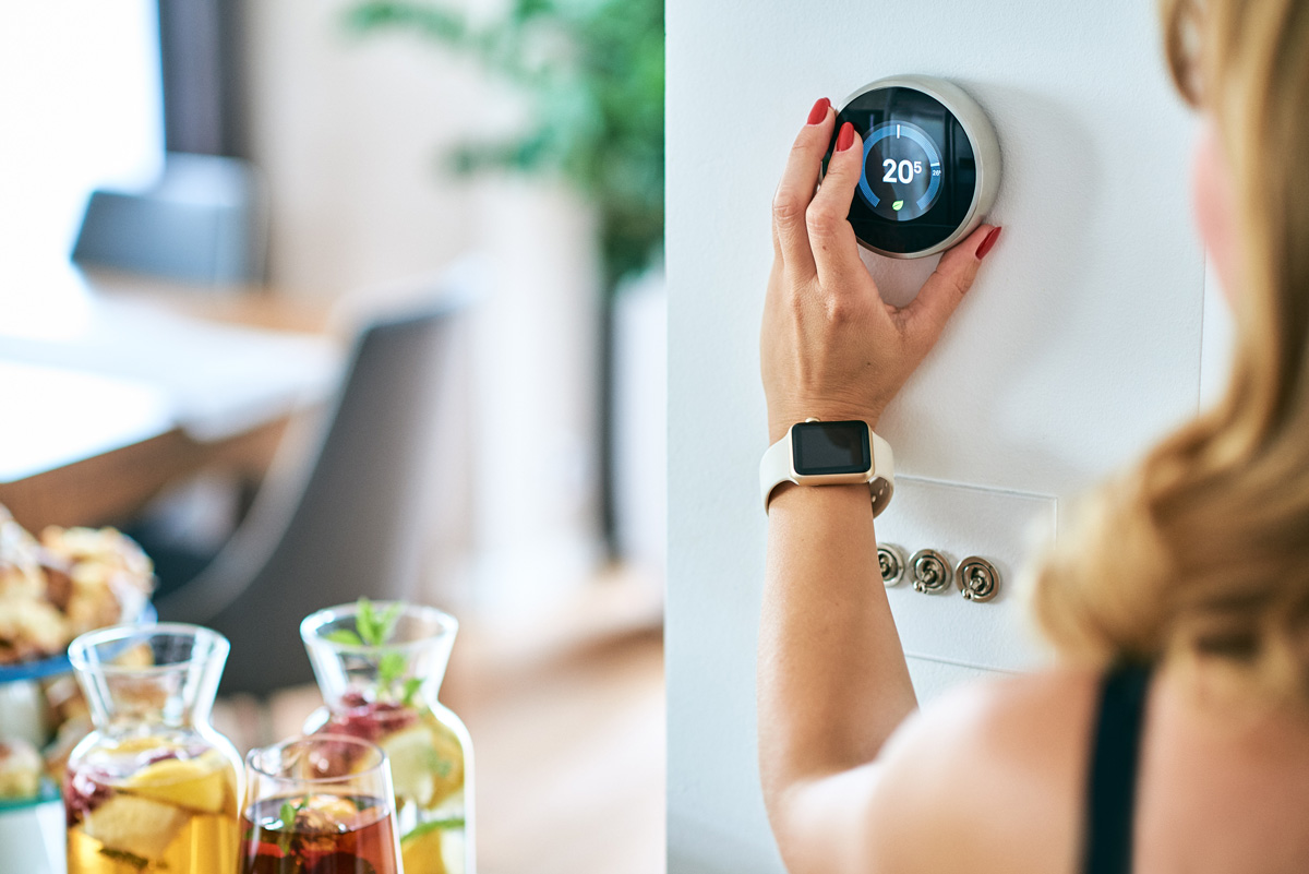 A woman adjusting an energy-efficient thermostat in El Paso.